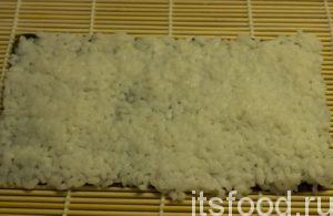 Закручиваем ролл листом нори внутрь. Отмерить 80 г. риса и распределить его всей поверхности лита. Раскладывать рис лучше слегка смоченными в воде руками. Рис должен быть чуть теплым и слегка влажным.