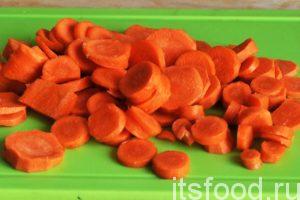 Нарежем очищенную морковь кружочками и добавим ее в сковородку. Все перемешаем и продолжаем тушить мясо в собственном и луковом соку. 
